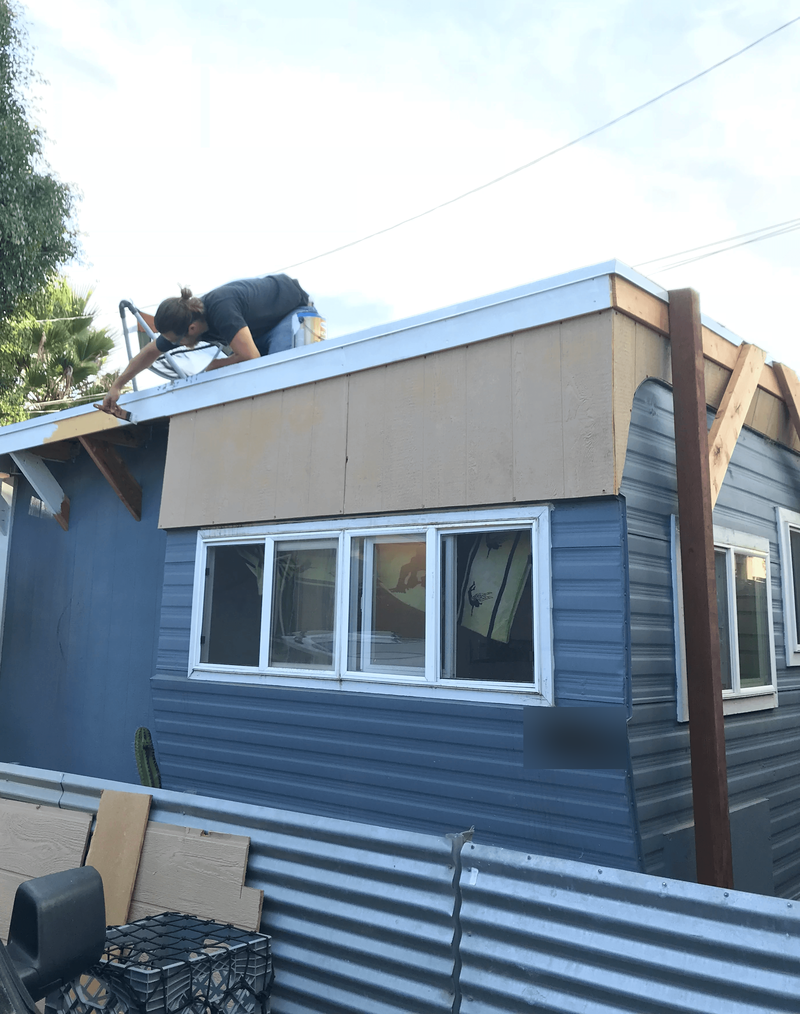 guy on top of roof of 1957 trailer blue