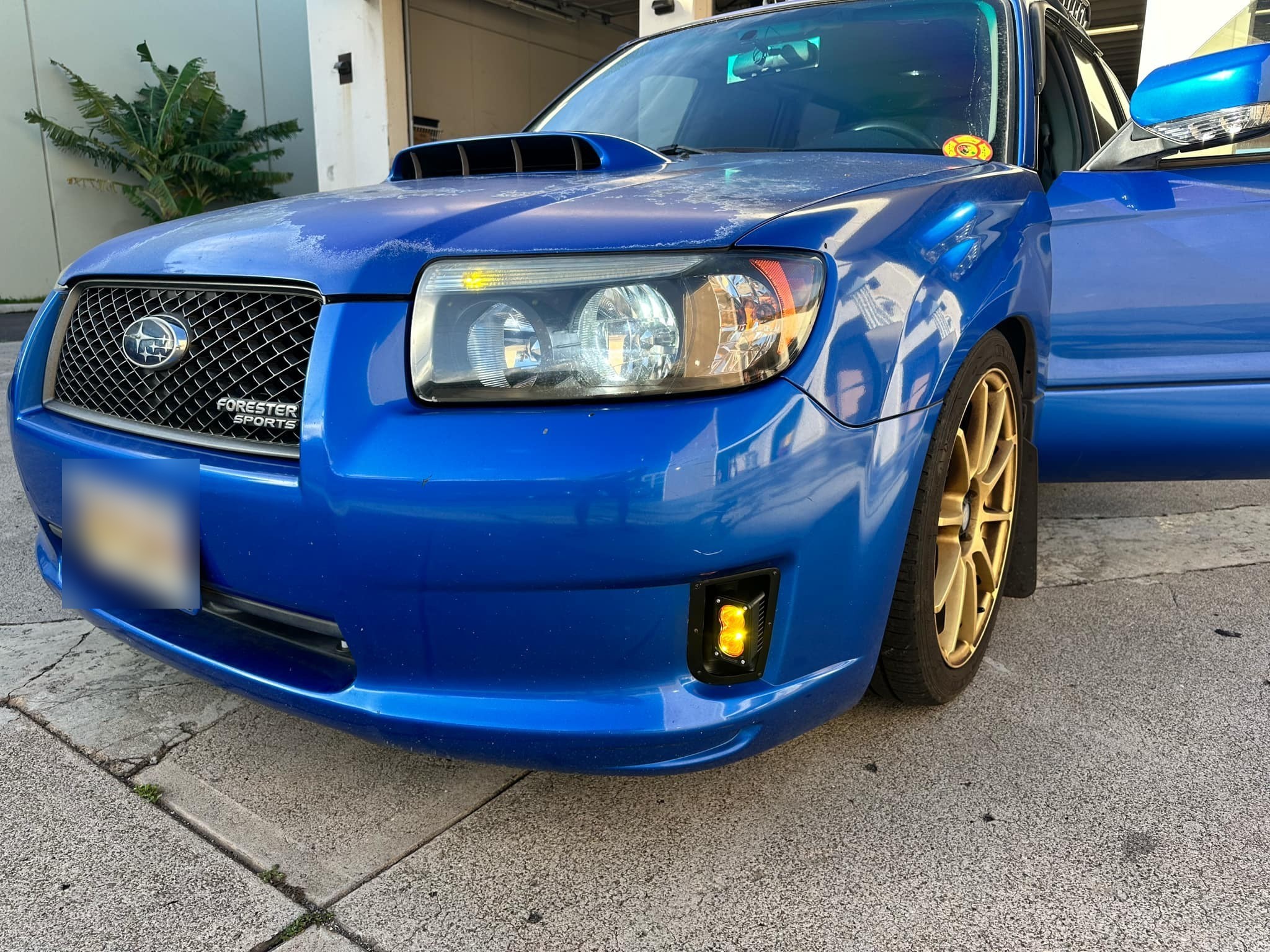 Front quarter view of the blue Forester showing the flush-mounted amber fog light