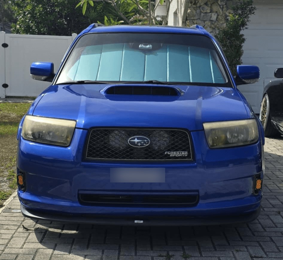 Head-on view of the blue Forester showing both amber fog lights in the bumper
