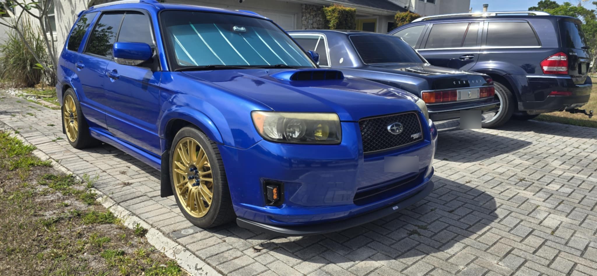 Front quarter view of the blue Forester parked on a paver driveway