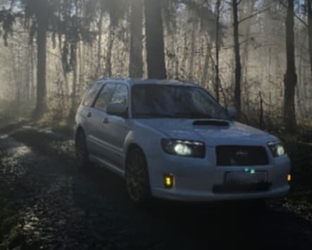 White Forester on a forest track with the amber fog lights glowing